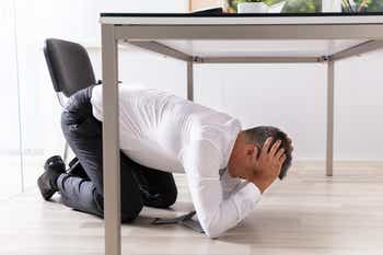 Man taking cover under table