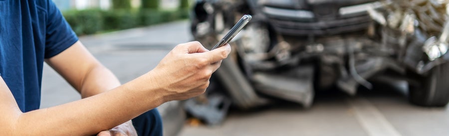 Man calling with phone to his insurance agent after traffic accident