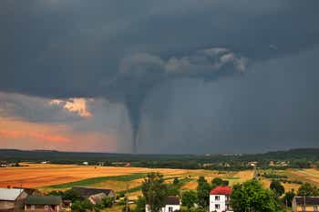 View of the serene countryside and stormy sky with a tornado in the background